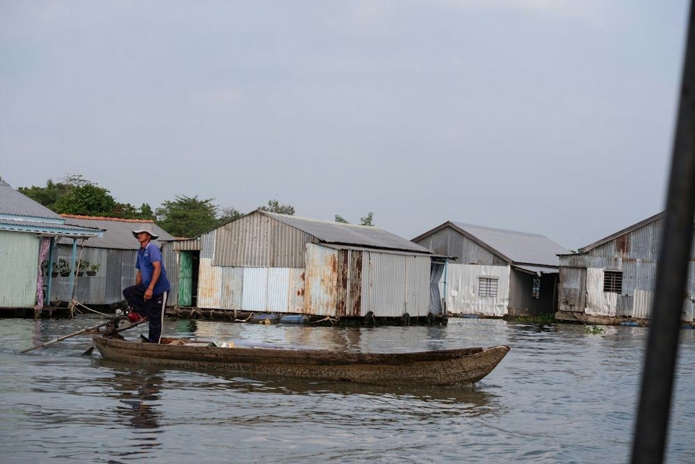A man stands in a small boat on a river in Vietnam