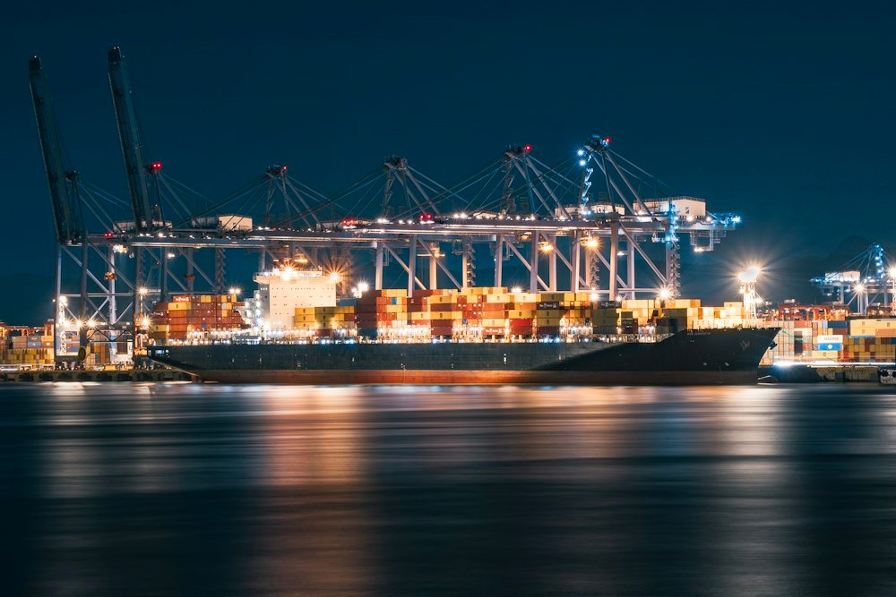 Container ship alongside brightly illuminated gantry cranes at Yantian Port, Shenzhen