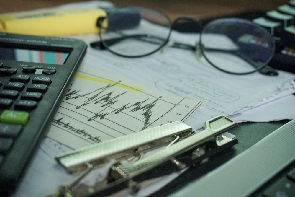Calculator, financial charts and glasses on a desk