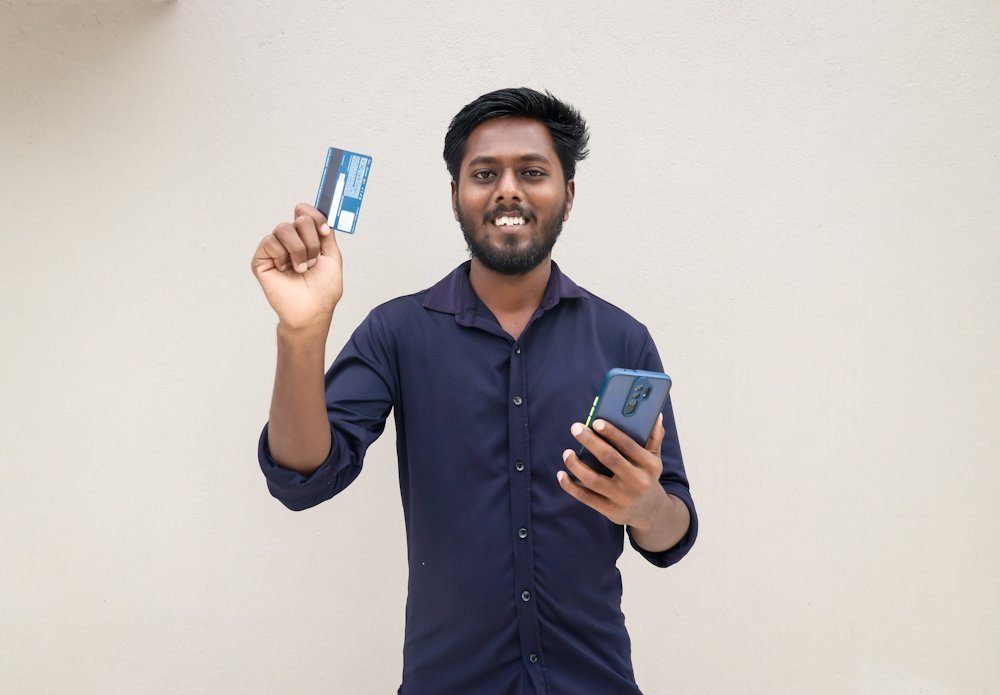 Man holding a debit card and smartphone in Tamil Nadu, India